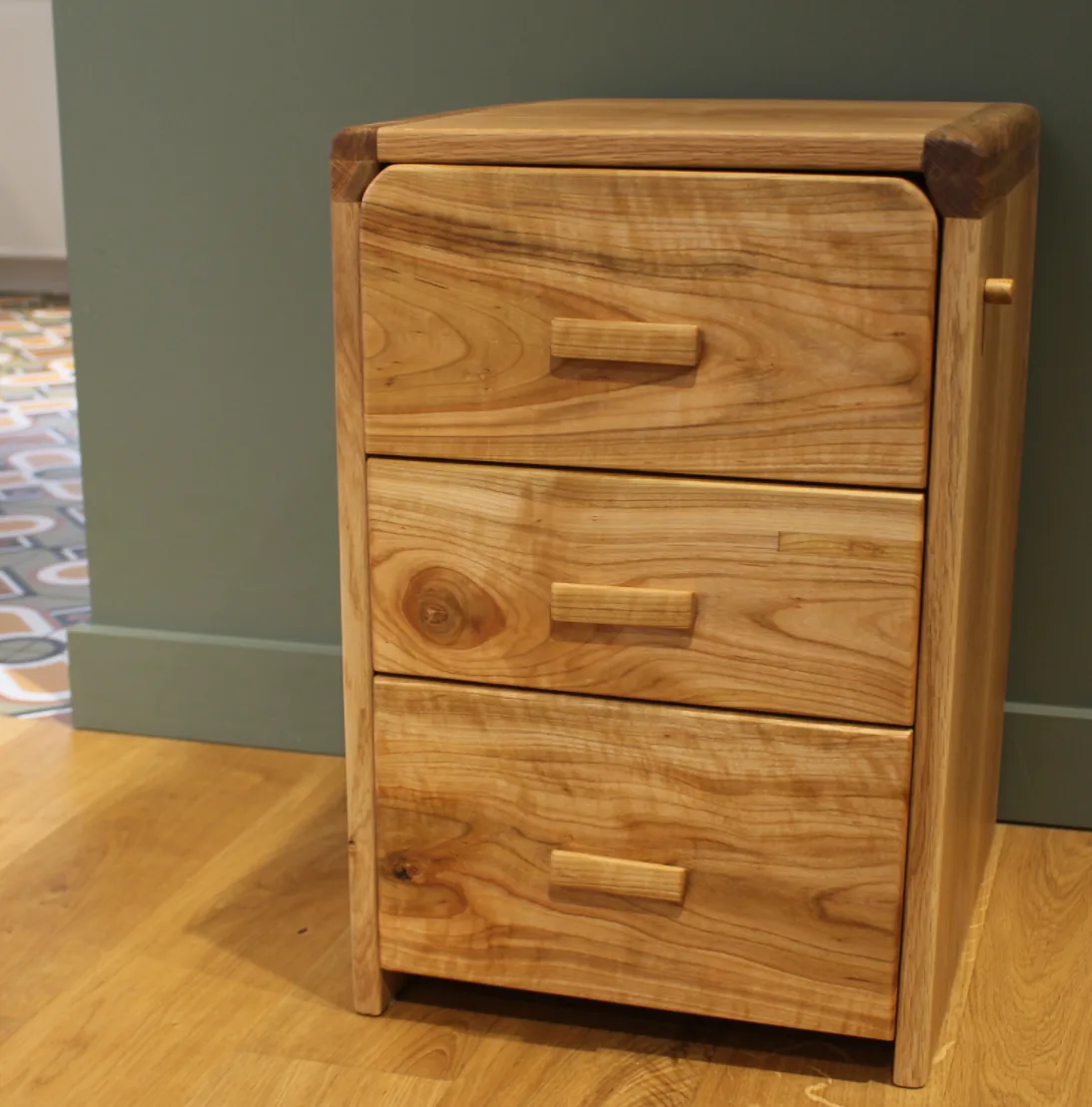 Andvari — under-desk cabinet in oak and cherry, three drawers, against the wall