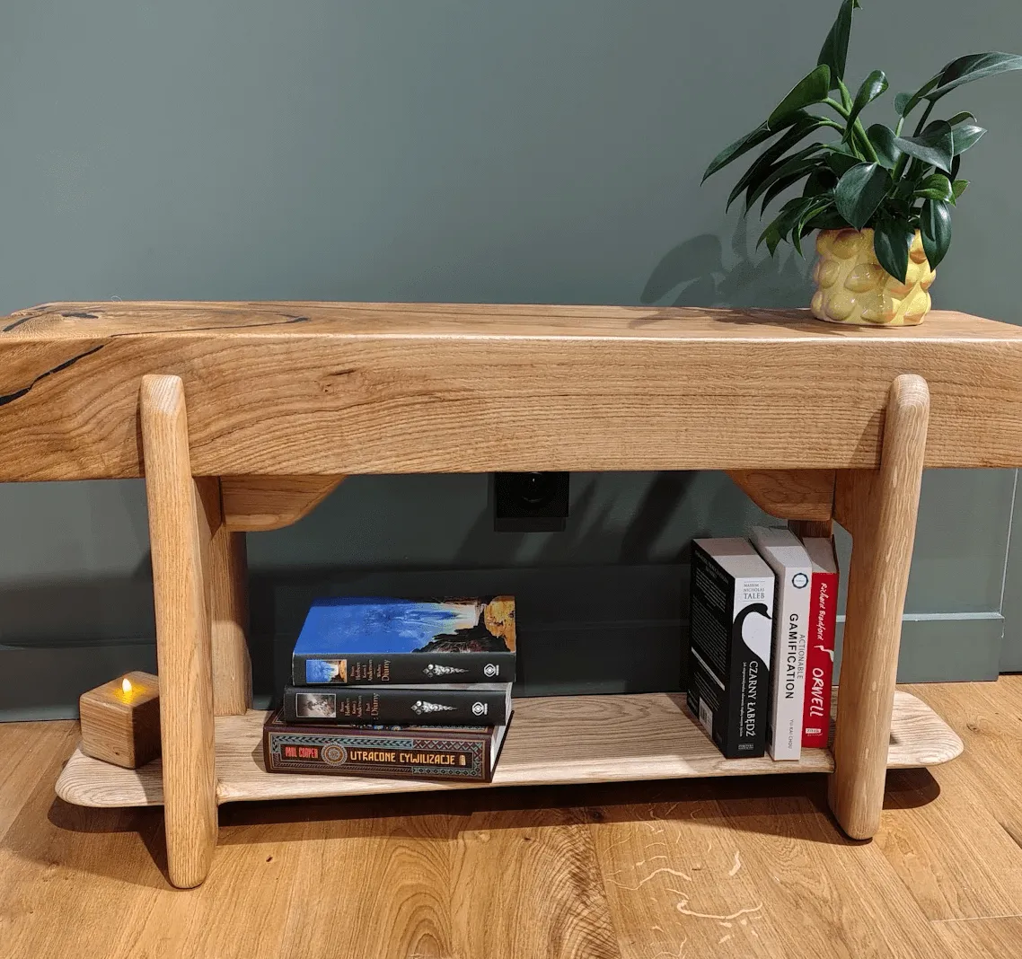 Ławka Feniks — dębowa belka z widocznymi bliznami, z półką na książki